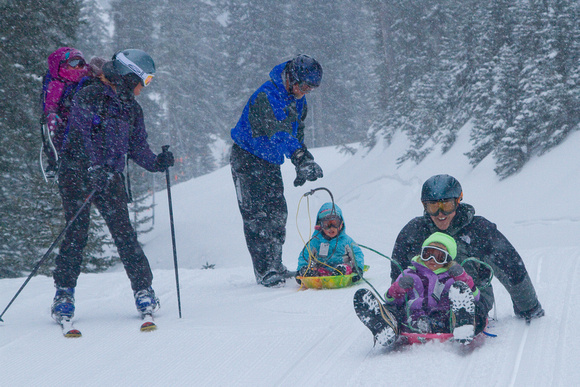 Little girls ski in backpacks; big girls sled w/ dads